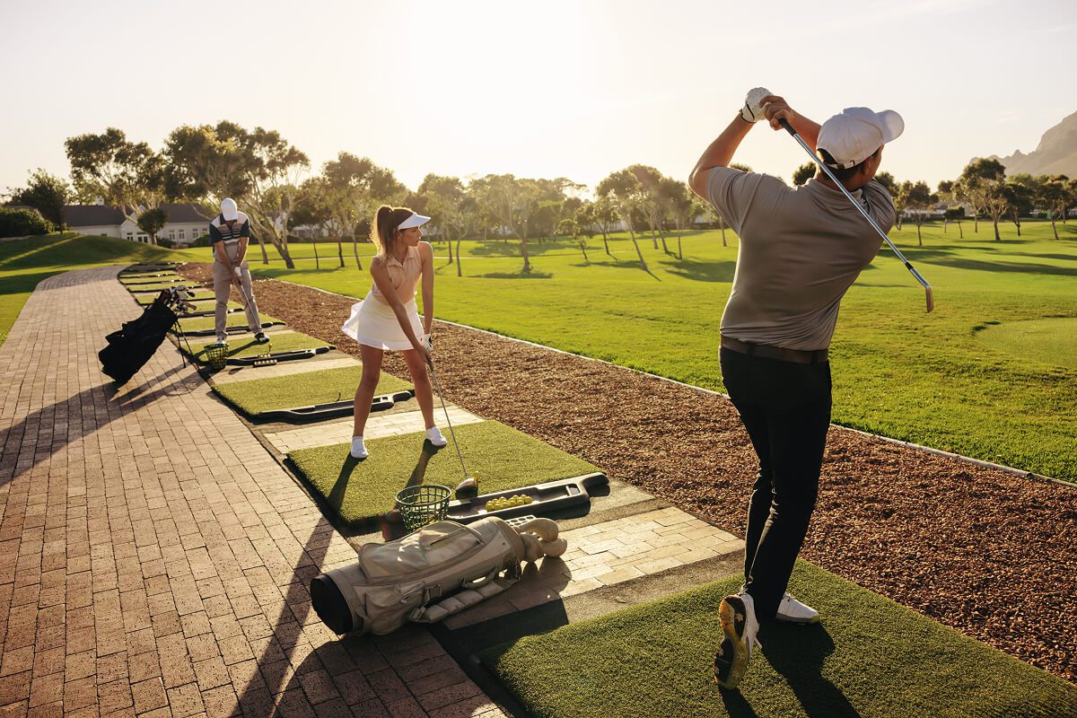 Golfers practicing swings on a driving range.